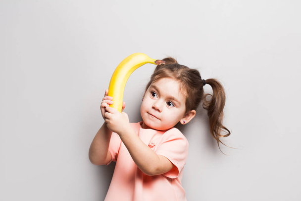 muotokuva pieni söpö hymyilevä tyttö tilalla banaani
 - Valokuva, kuva