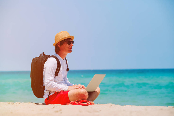 afstandsbediening werken - man met laptop op strand - Foto, afbeelding
