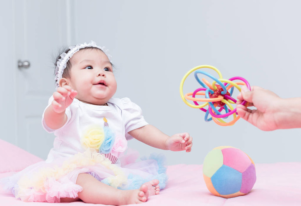 bonito menina bebê sorriso e jogar brinquedo com a mãe mão
 - Foto, Imagem