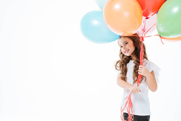 Smiling cute little girl standing and holding colorful balloons - Foto, afbeelding