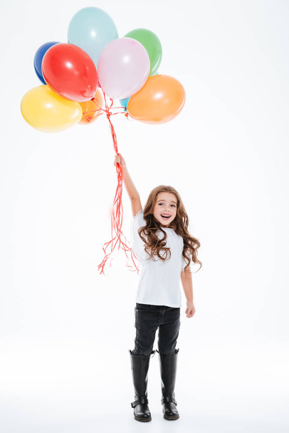 Full length of little girl standing and holding colorful balloons - Fotoğraf, Görsel