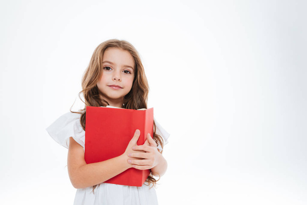 charmantes kleines Mädchen stehend und mit rotem Buch in der Hand - Foto, Bild