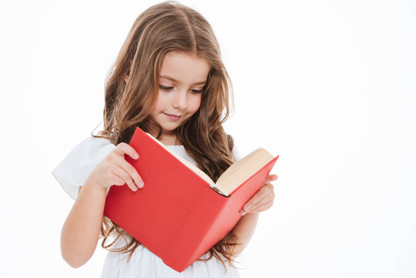 Lovely little girl standing and reading book - 写真・画像