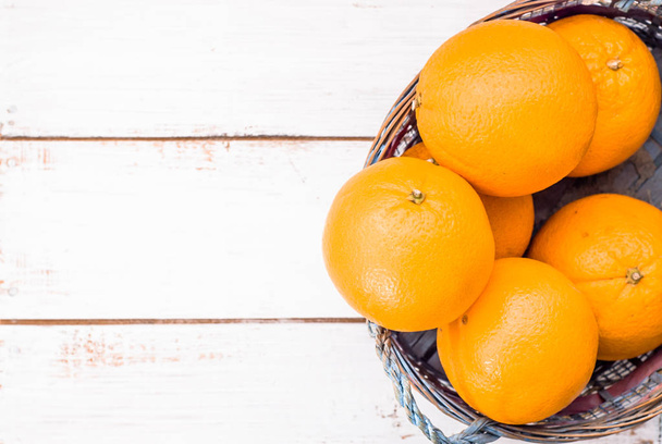Fresh oranges in basket on wood background - Foto, afbeelding