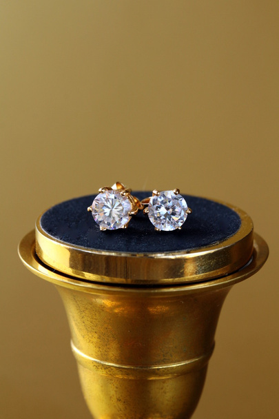 Orecchini in oro stallone con diamanti su sfondo oro
 - Foto, immagini