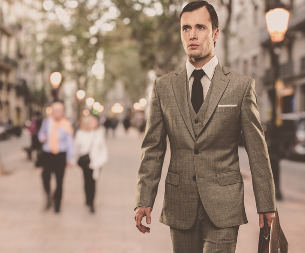 Mann im klassischen grauen Anzug mit Aktentasche geht draußen spazieren - Foto, Bild