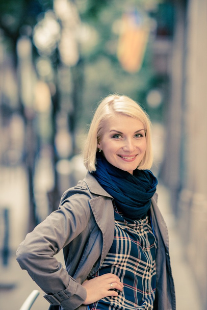 Beautiful smiling blond woman wearing blue scarf outdoors - Photo, Image