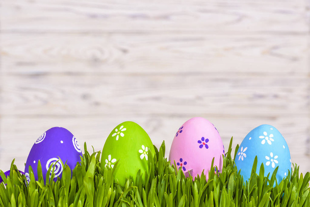 Huevos de Pascua de color pastel en hierba verde sobre fondo rústico de madera
. - Foto, imagen