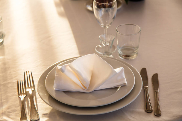 Servilleta de lino en un plato en la mesa cubierta con una tabla blanca
 - Foto, imagen