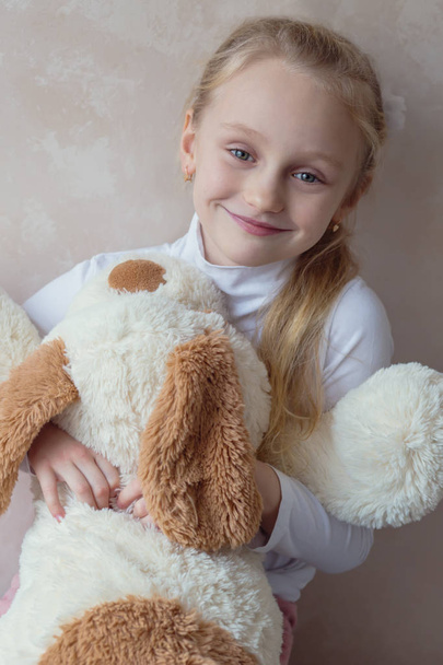 Smiling little girl holding a toy dog  - Photo, Image