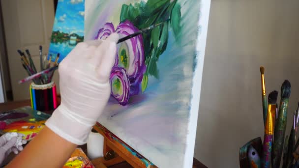 крупним планом жіноча рука художника яка малює квіти пензлем на полотні і сидить у мольберті в художній студії
. - Кадри, відео