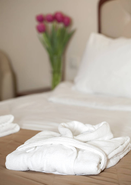 white bathrobe on the bed - Фото, изображение