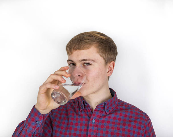 tiener jongen drinkt een glas water - Foto, afbeelding