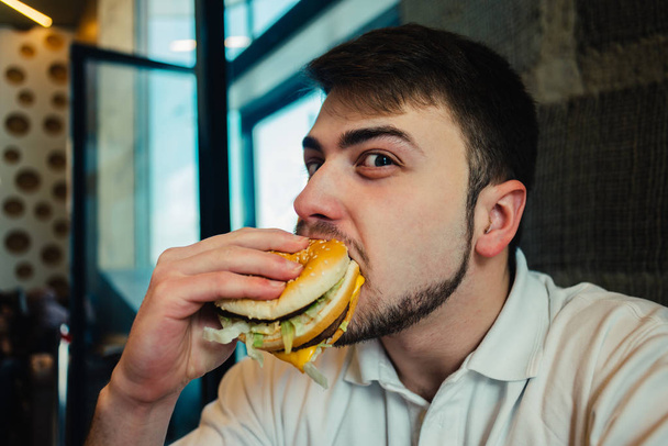 a young man with a beard enjoys fast food - Foto, Imagen