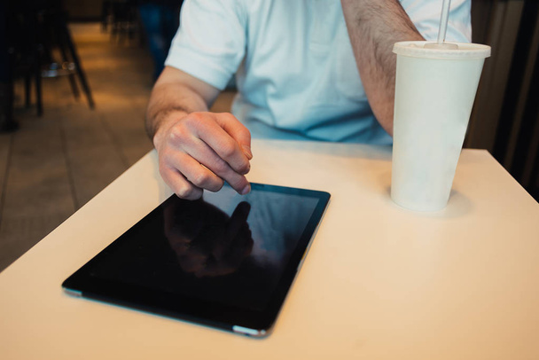 jovem usa computador tablet no restaurante acolhedor e bebe refrigerante
 - Foto, Imagem