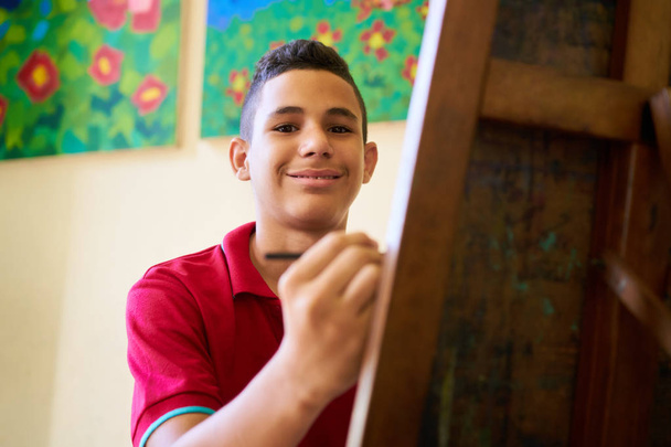 美術学校は、カメラに笑顔の幸せなヒスパニック系男子生徒 - 写真・画像