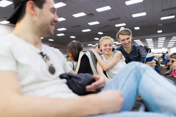 Группа молодёжи в зале ожидания аэропорта Пара билетов в ожидании отъезда Счастливые улыбающиеся друзья
 - Фото, изображение