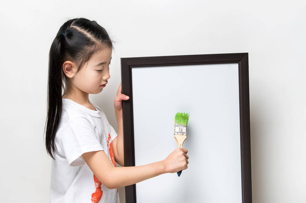 Pretty Asia little girl with a brush and white banner - Foto, imagen