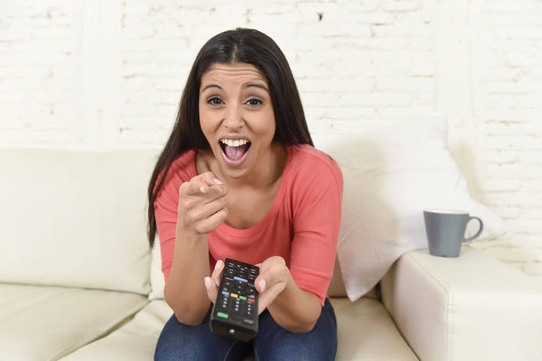 aantrekkelijke Latijns-vrouw in huis banklaag lachen en glimlachen gelukkig televisiekijken  - Foto, afbeelding