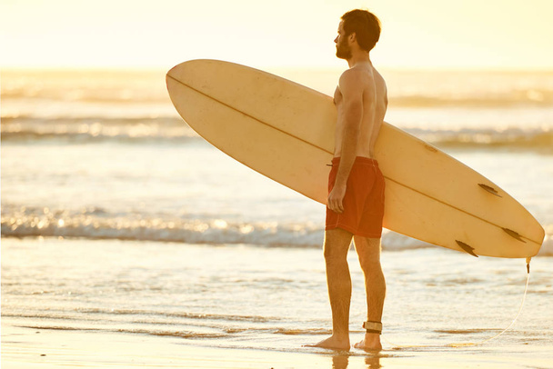 Profile of man holding a surfboard on the beach - Fotografie, Obrázek