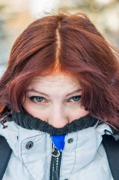 red-haired girl is cold and wrapped in a jacket - Fotó, kép