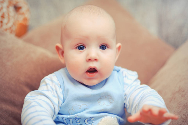 bebé de ojos azules en el sofá
 - Foto, Imagen