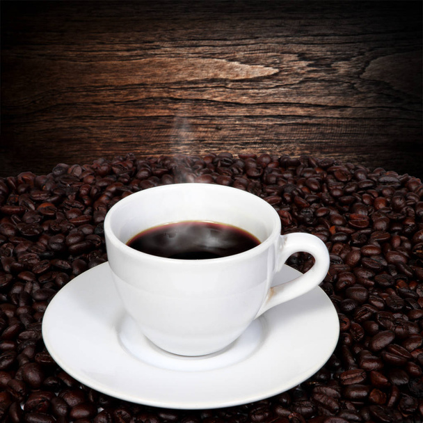 Black coffee and coffee beans with smoke on wood - Photo, Image