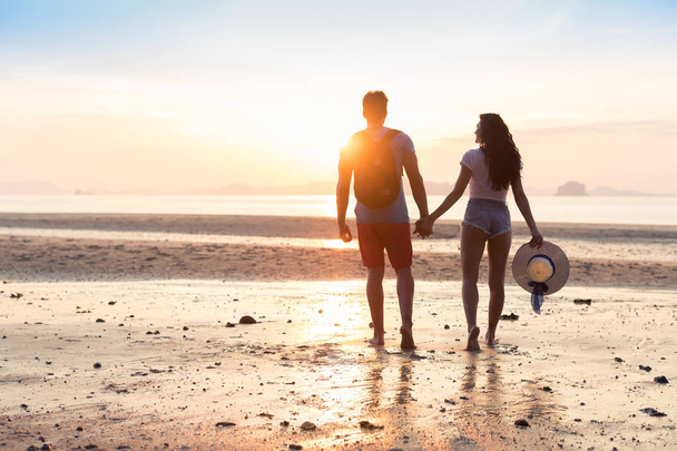Para na plaży w wakacje zachód słońca, pięknych młodych ludzi w miłości, spacery, kobieta mężczyzna, trzymając się za ręce - Zdjęcie, obraz