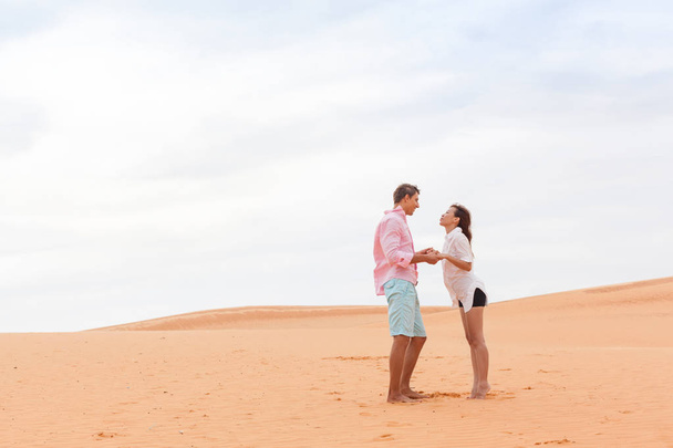 Молодий чоловік жінка в пустелі красива пара азіатська дівчина і хлопець тримати руки пісок дюна
 - Фото, зображення