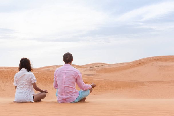Man And Woman In Desert Sitting Lotus Pose Young Couple Meditating - 写真・画像