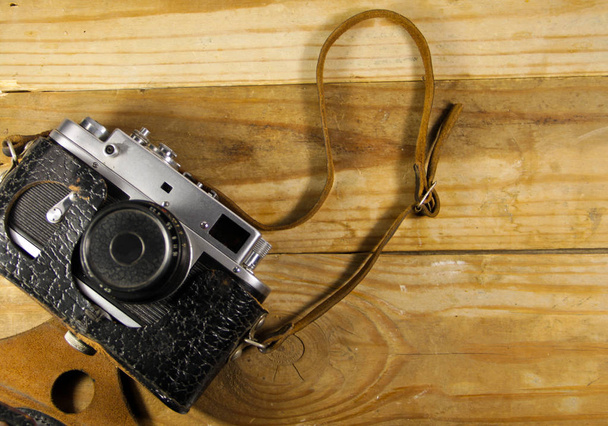 Старая ретро камера в кожаном чехле на деревянном фоне
 - Фото, изображение