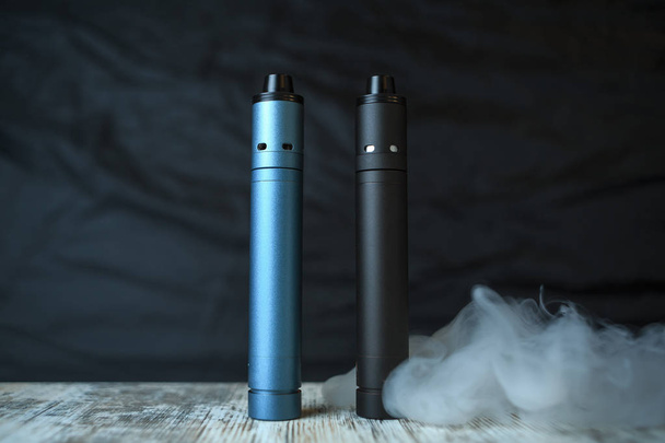 Electronic cigaretts and a cloud of steam on the table. Mechanical mod. ENDS. - Zdjęcie, obraz