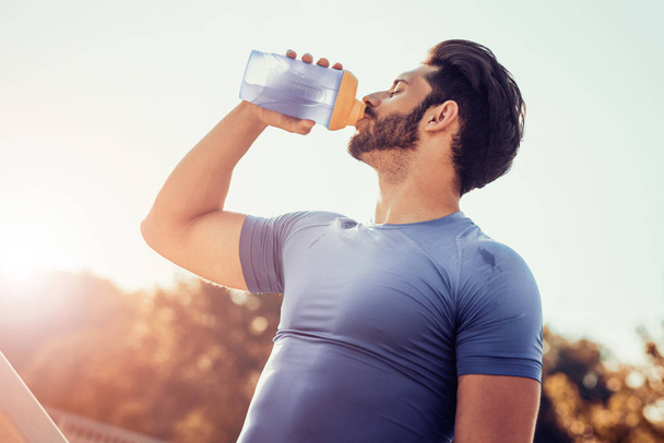 Чоловік п'є воду після тренування
 - Фото, зображення
