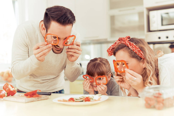 Счастливая молодая семья готовит обед
 - Фото, изображение