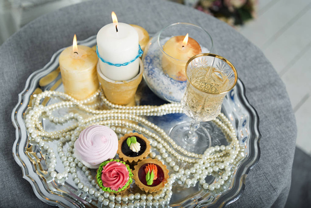 Κεριά, κέικ, μαργαριτάρια σε ασημένιο δίσκο. - Φωτογραφία, εικόνα