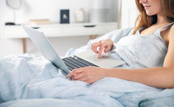 Young girl with laptop checking social media in bed at home - Photo, image