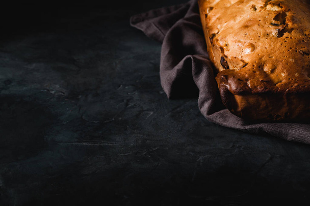Fresh bread with dried fruits on dark rustic background - Fotó, kép