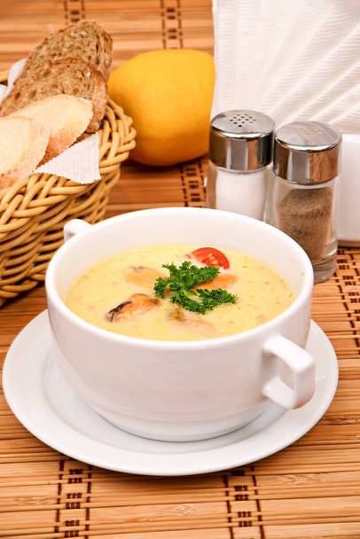 Pureer de soep van maïs met mosselen met peterselie in een witte plaat - Foto, afbeelding