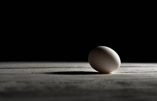 Hühnchen roh weißes Ei auf weißem Tisch mit schwarzem Hintergrund - Foto, Bild