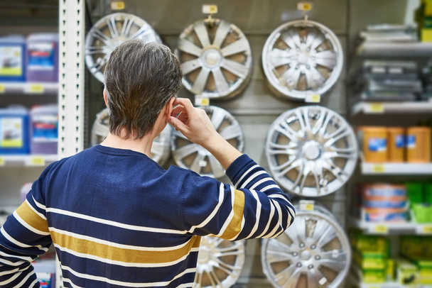 El hombre elige ruedas de aleación para sus ruedas de coche en el supermercado
 - Foto, Imagen