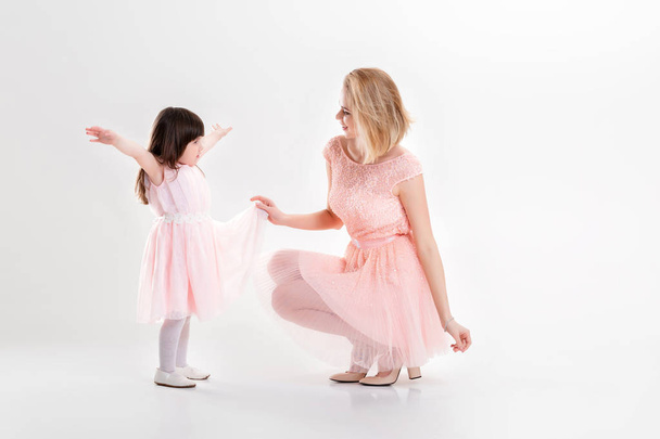 blonde mom and sweet little daughter in pink dresses princesses - Фото, изображение