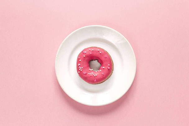 Donut mit Sahnehäubchen auf Teller auf rosa Hintergrund. Ansicht von oben. - Foto, Bild