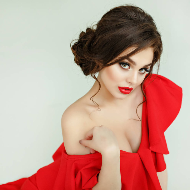 Elegant sexy brunette girl in a red dress lying on the floor, st - Foto, afbeelding