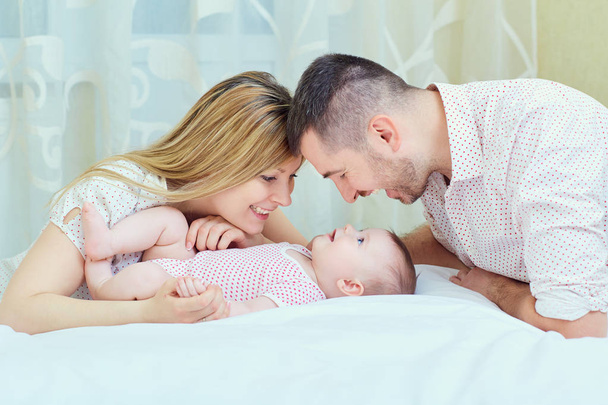 Mother and father playing with baby on the bed. A happy family - Fotografie, Obrázek