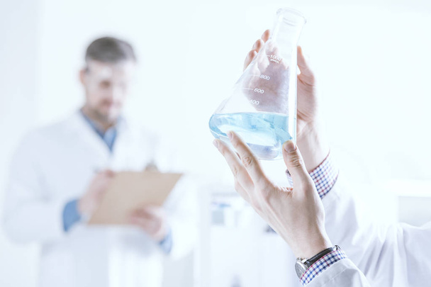 Scientist holding vessel with liquid - Photo, image