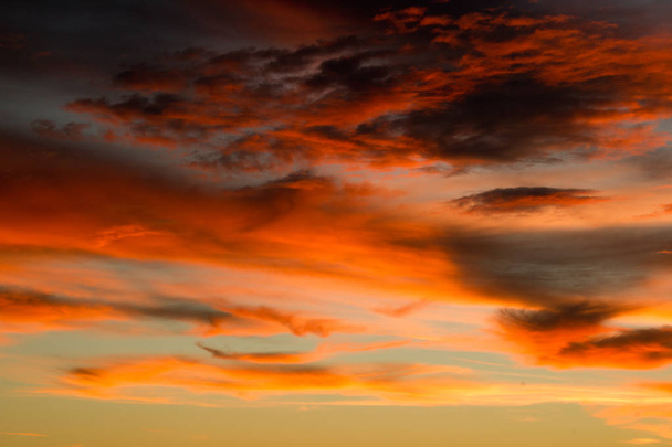 Pomarańczowe niebo wypełnione chmury podczas zachodu słońca. - Zdjęcie, obraz