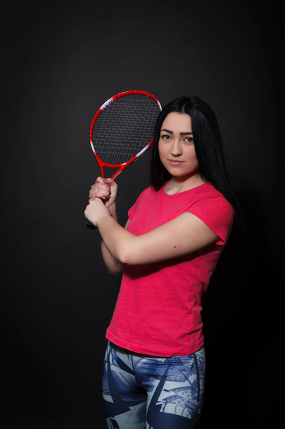 Młoda kobieta z rakietą tenisową na czarnym tle - Zdjęcie, obraz