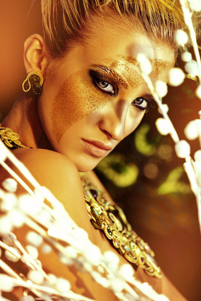 Sensuele blonde vrouw met gouden stof op het gezicht - Foto, afbeelding