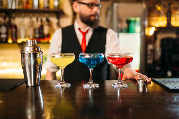 barman y tres bebidas en copas de vino
 - Foto, imagen