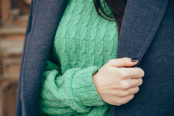 Details of women's clothing. Close-up hand of a woman in a sweater and coat. - Foto, afbeelding